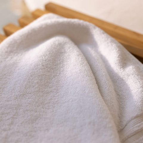 Nahaufnahme eines flauschigen weißen Badetuchs mit weicher Frotteestruktur in hochwertiger Hotelqualität.