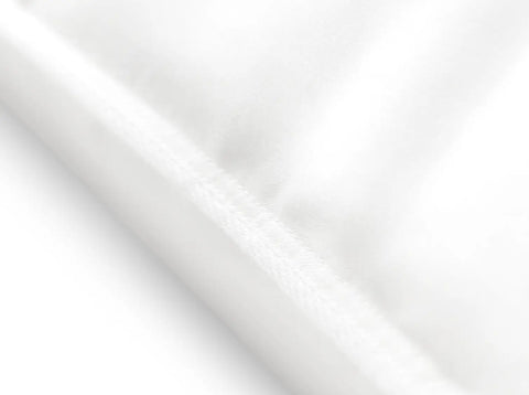 Weicher weißer Stoff mit sanften Falten in Nahaufnahme, der hochwertige Materialien, Komfort und sorgfältige Verarbeitung von Betttextilien symbolisiert.