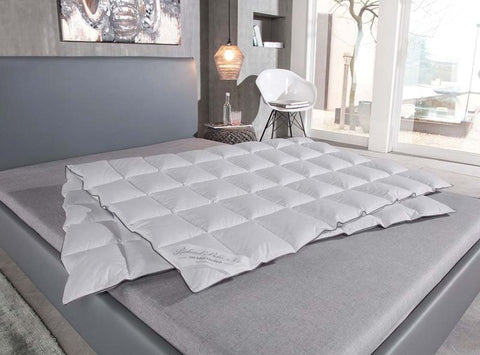 Hochwertige Eiderdaunendecke mit Kassettensteppung auf elegantem Designerbett für optimalen Schlafkomfort und gleichmäßige Wärmeverteilung