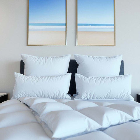 Mehrere Excellence Gänsedaunenkopfkissen auf einem stilvoll eingerichteten Bett mit hochwertiger Bettwäsche für ein exklusives Hotelgefühl zu Hause.