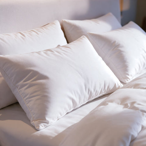 Mehrere HANSE Premium Natural Hybrid Kissen im Sonnenlicht am Kopfteil eines Hotelbetts