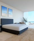 Modernes Schlafzimmer mit weißem Select Spannbettlaken auf einem eleganten Boxspringbett vor heller Fensterfront mit Meerblick